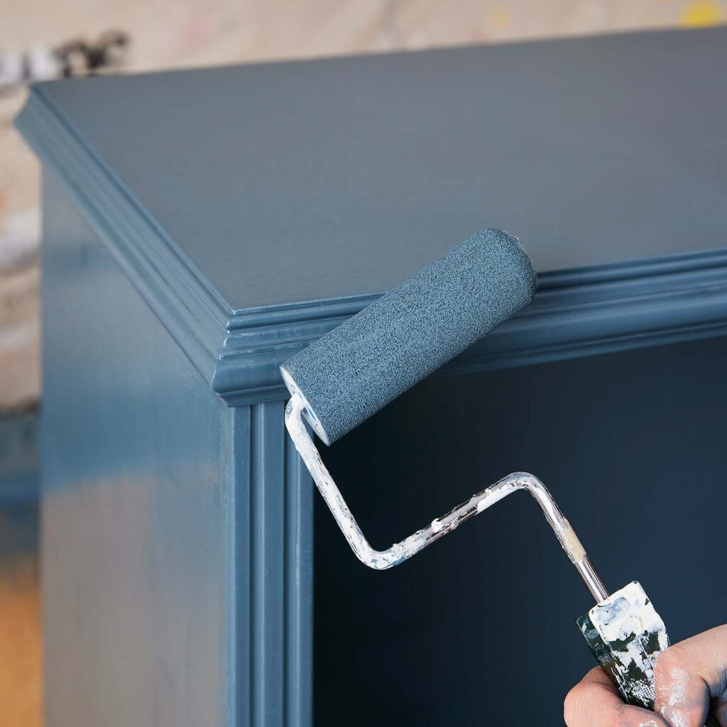 A roller painting the chest of drawers