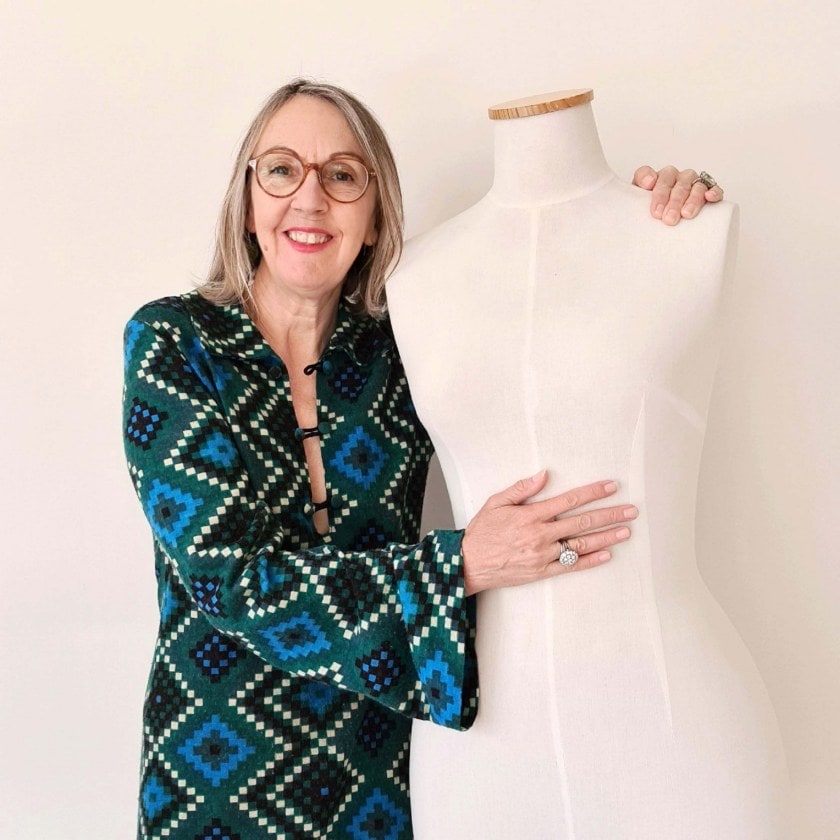 Dianne Ludwig in a vibrant dress next to a bare mannequin