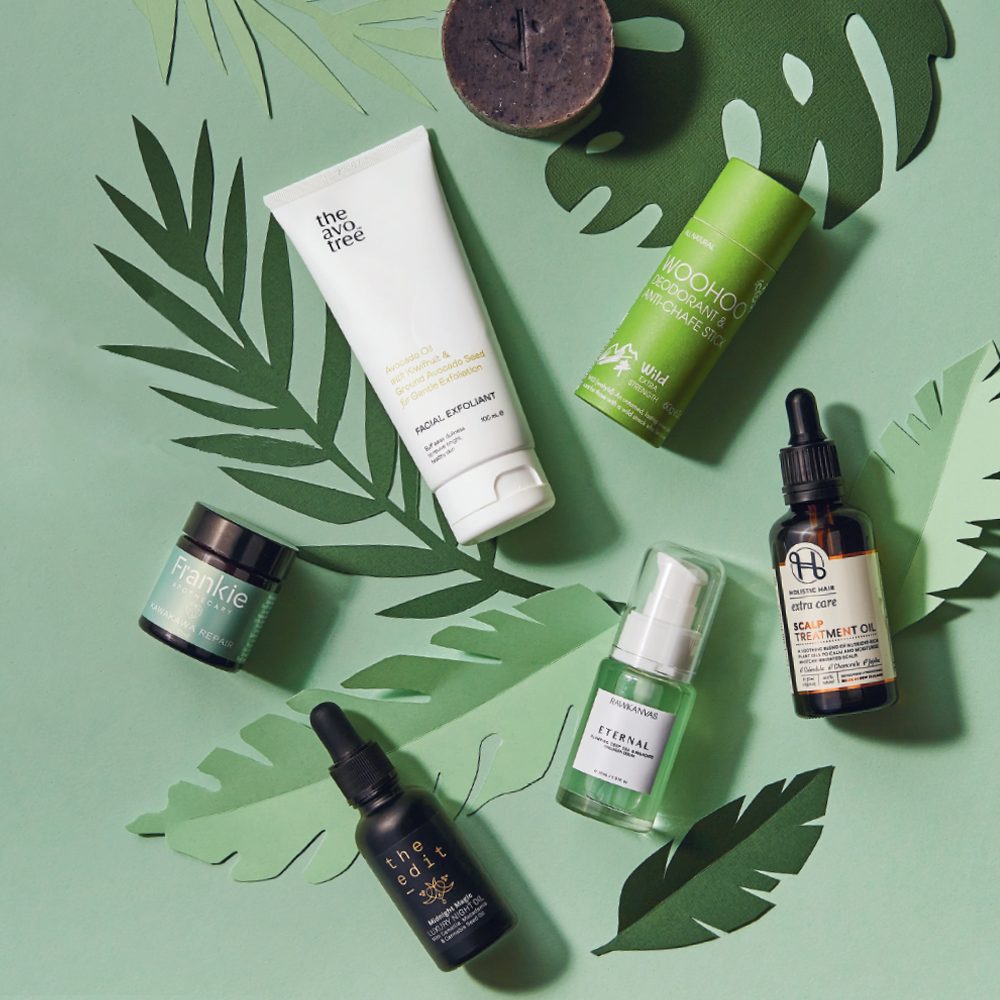 Collection of natural skincare and hair products on a green background with paper leaf cut outs