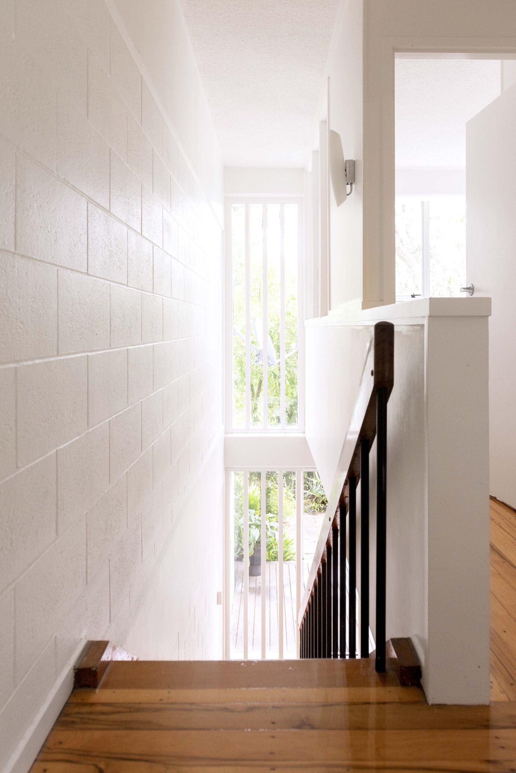 Top of stairs with polished wooden floors and tall windows