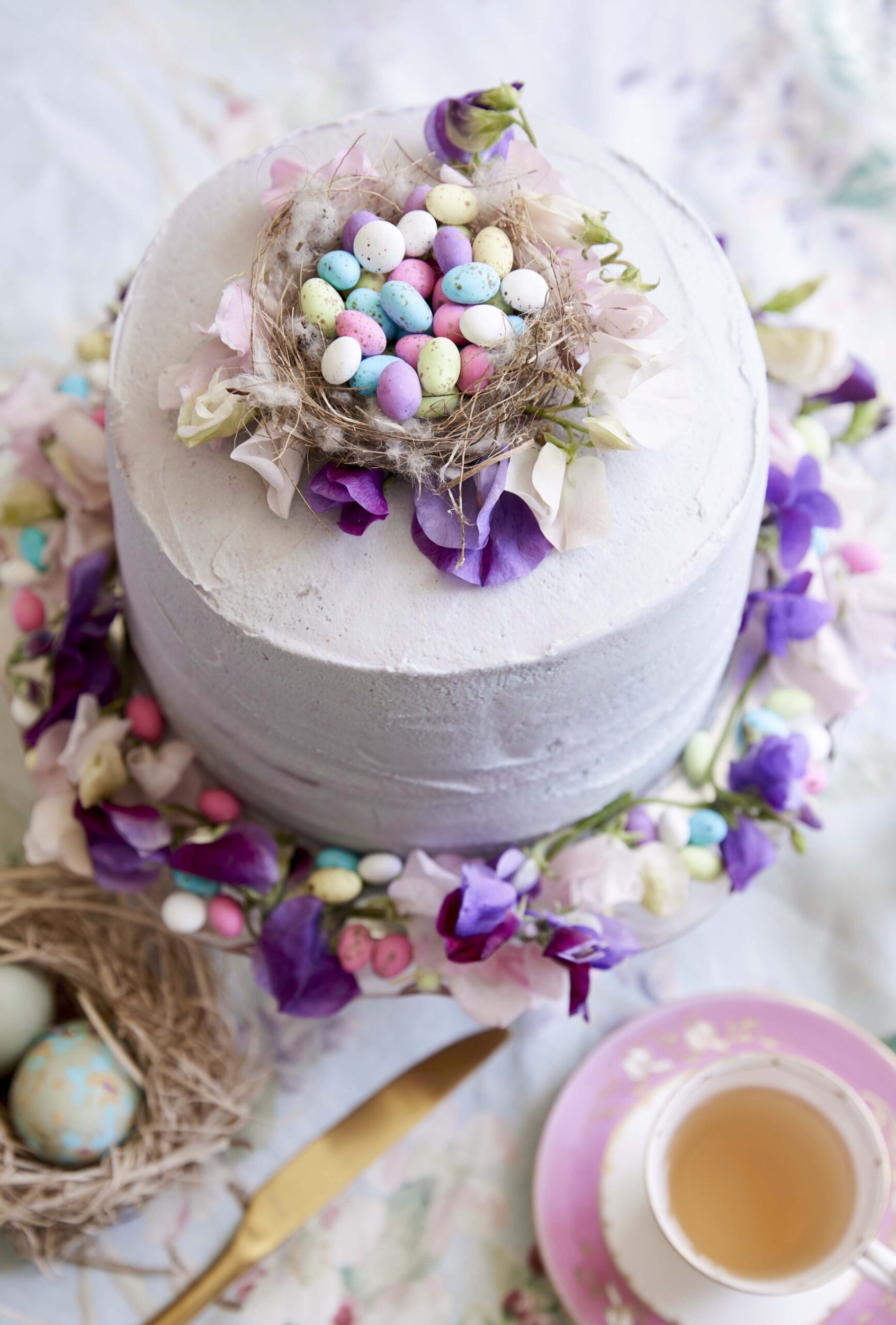 Cake with purple frosting, flowers and a bird's nest filled with Easter eggs