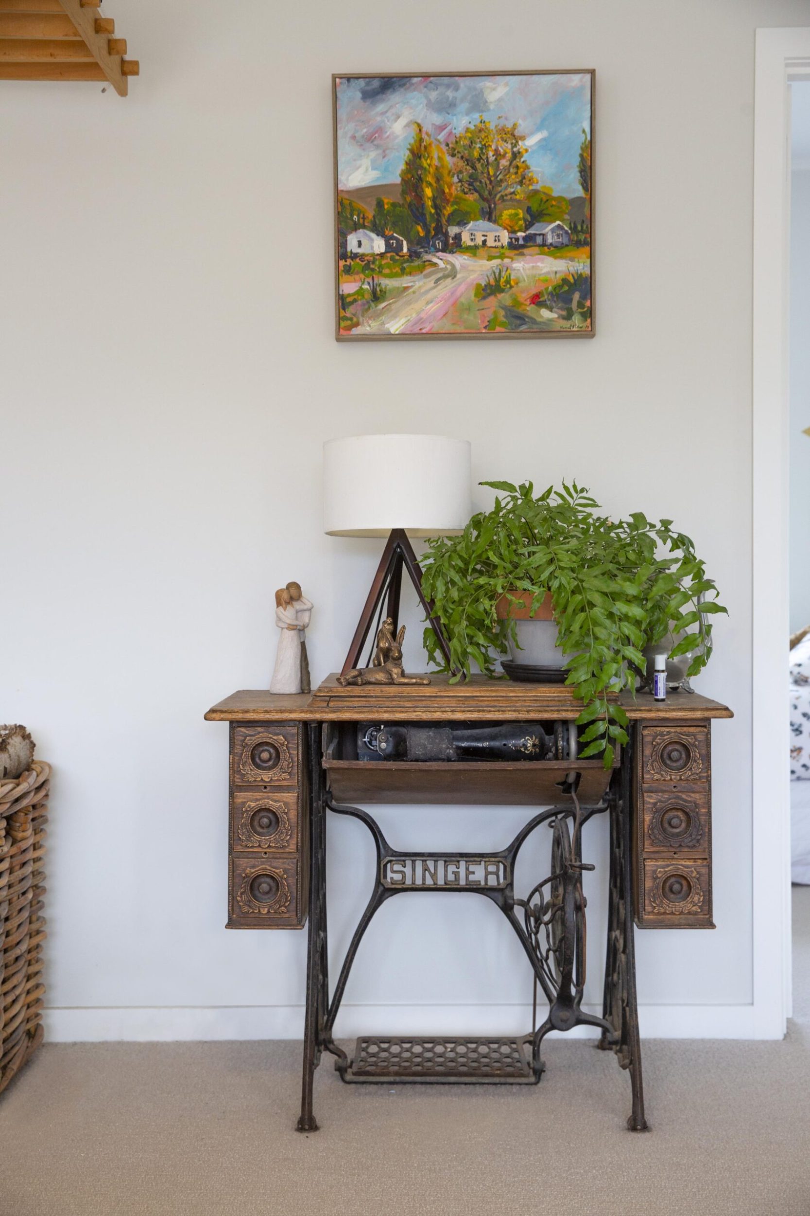 A vintage table made out of a repurposed Singer sewing machine placed against light blue wall