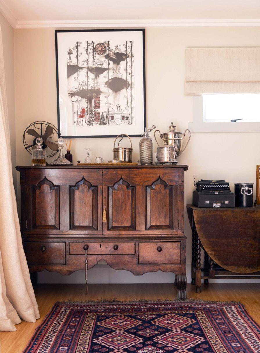 A brown vintage cabinet with an assortment of vintage decorative items on top