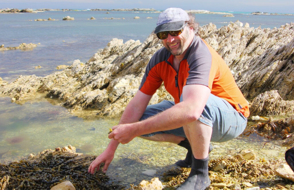 Peter Langlands holding seaweed on sea shore