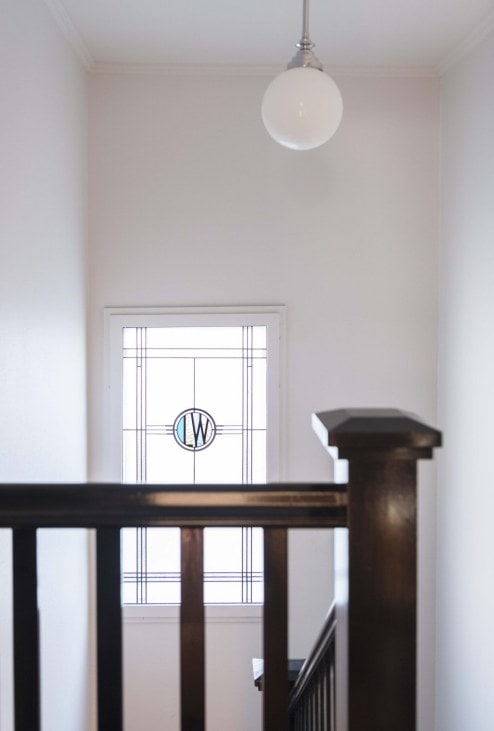 White room with a vintage window and dark brown stair banister