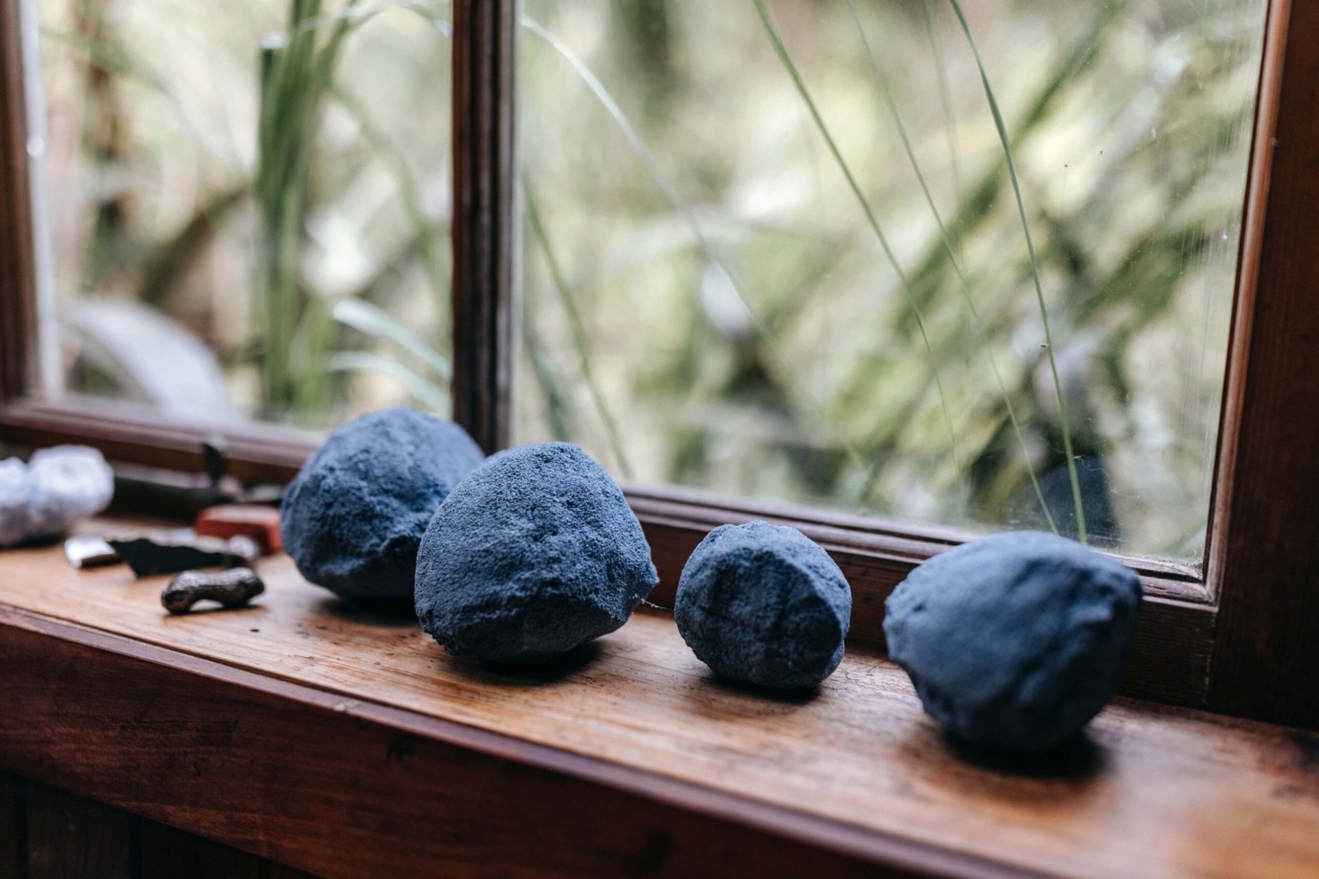 Black round art installations by artist Kate Newby on a wooden windowsill