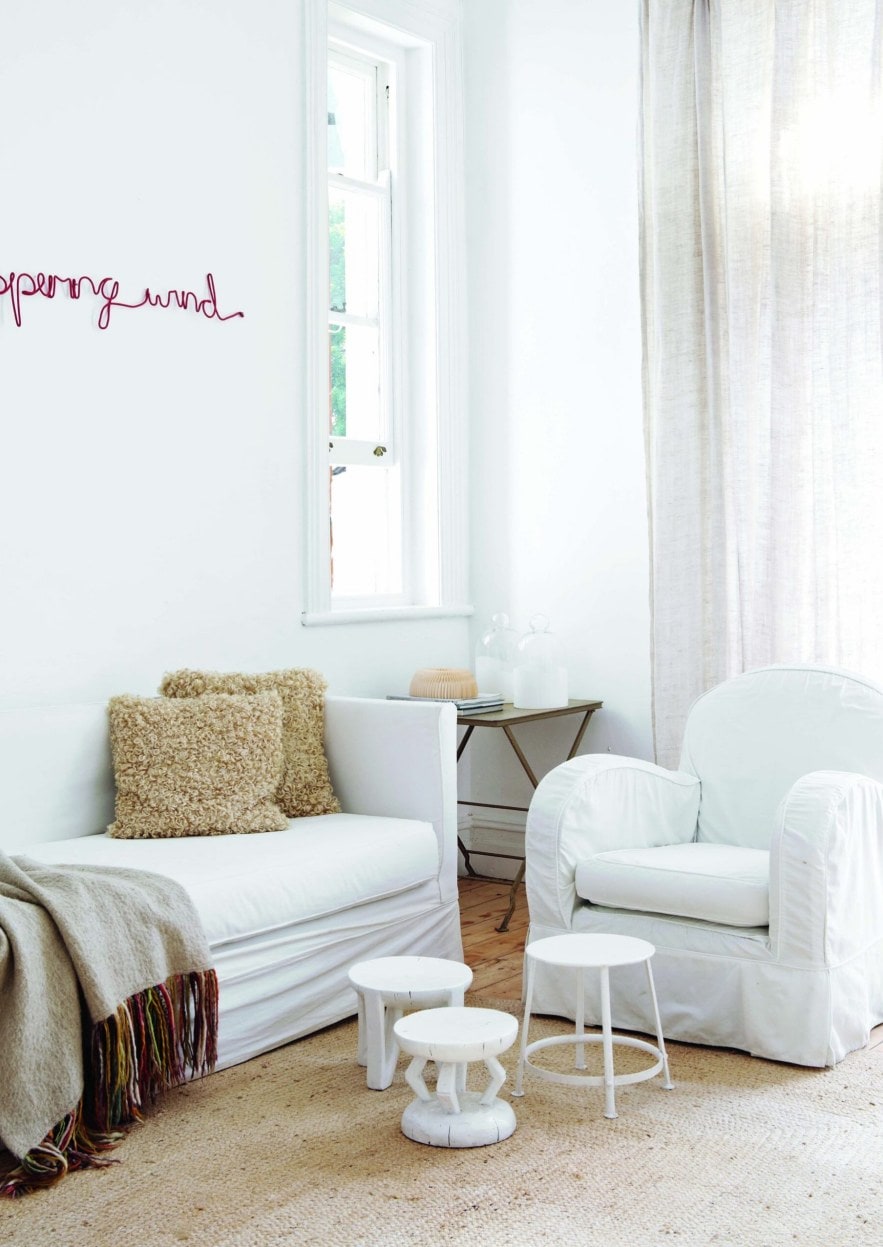 White living room with white couches and chairs, white muslin curtains and beige carpet