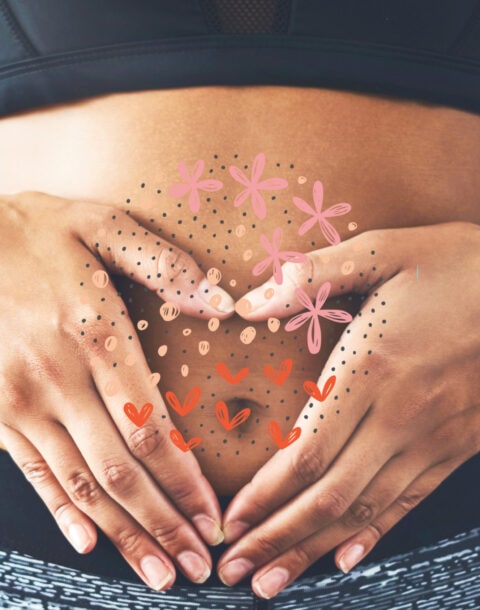 Close up of woman's hands holding stomach with drawings of hearts and flowers