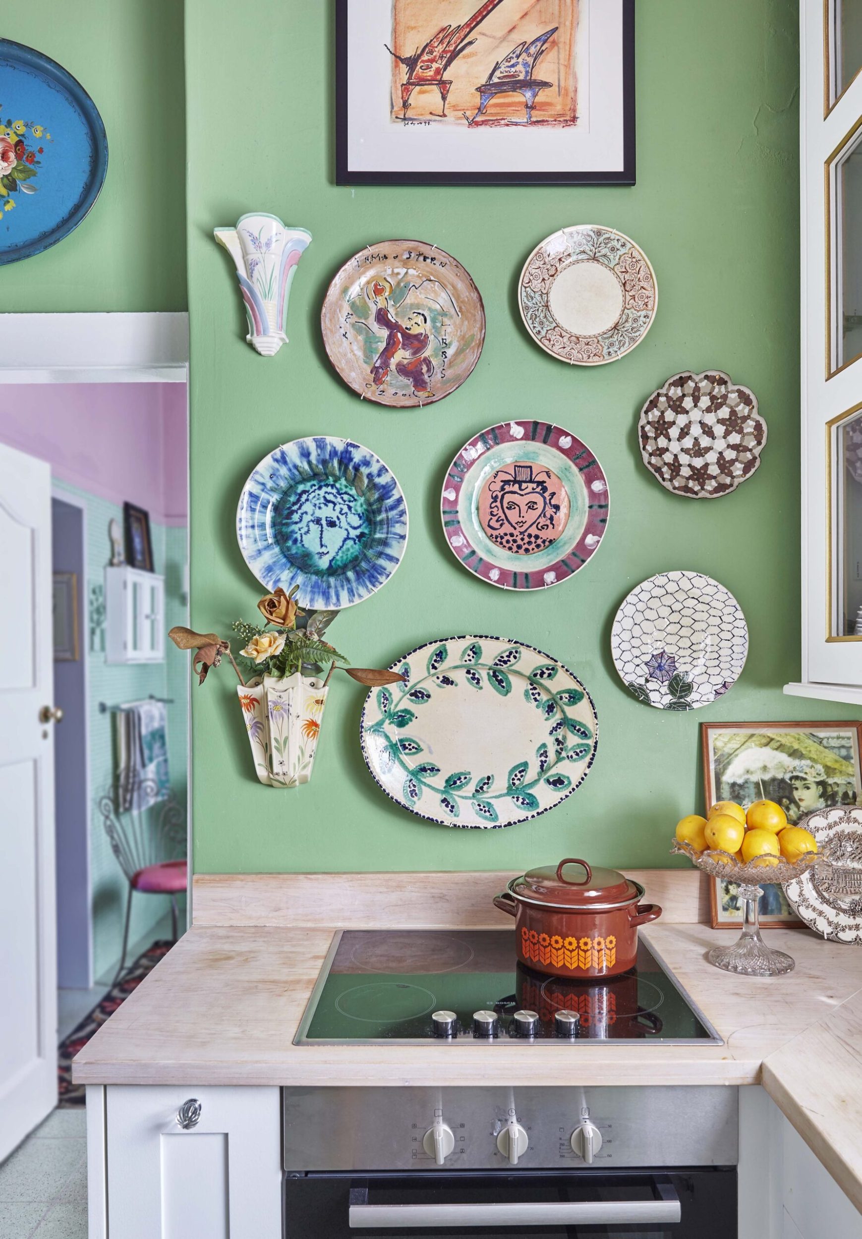 Kitchen stove set in a wood benchtop against a green wall with hanging ceramic plates