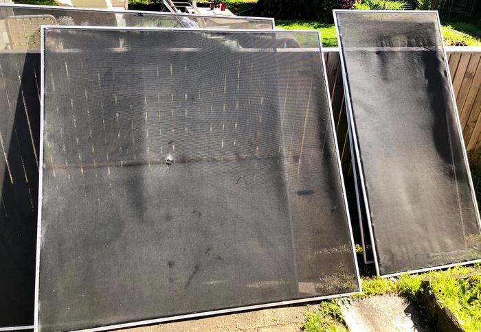 Old fly screens leaning against a fence