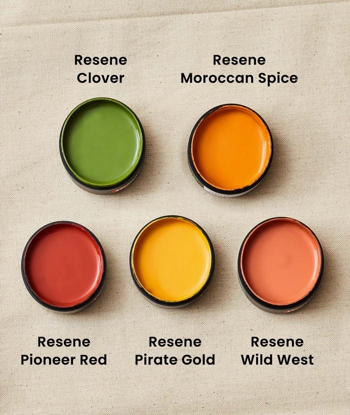 A collection of Resene Clover, Moroccan Spice, Pioneer Red, Pirate Gold and Wild West test pots on a beige background