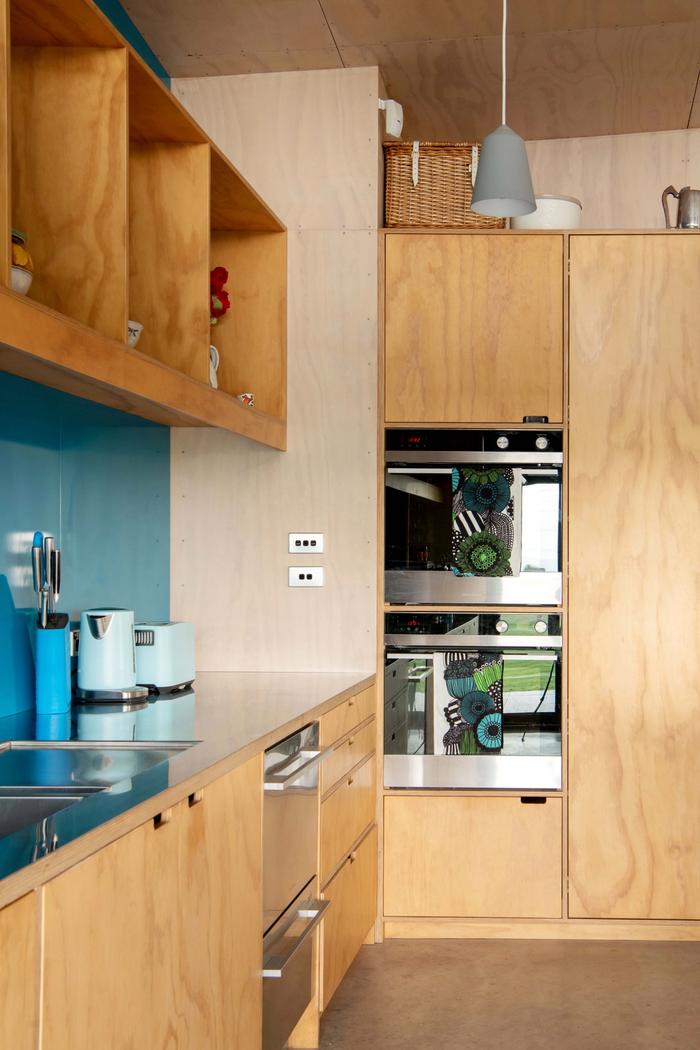 A plywood kitchen with a teal backsplash