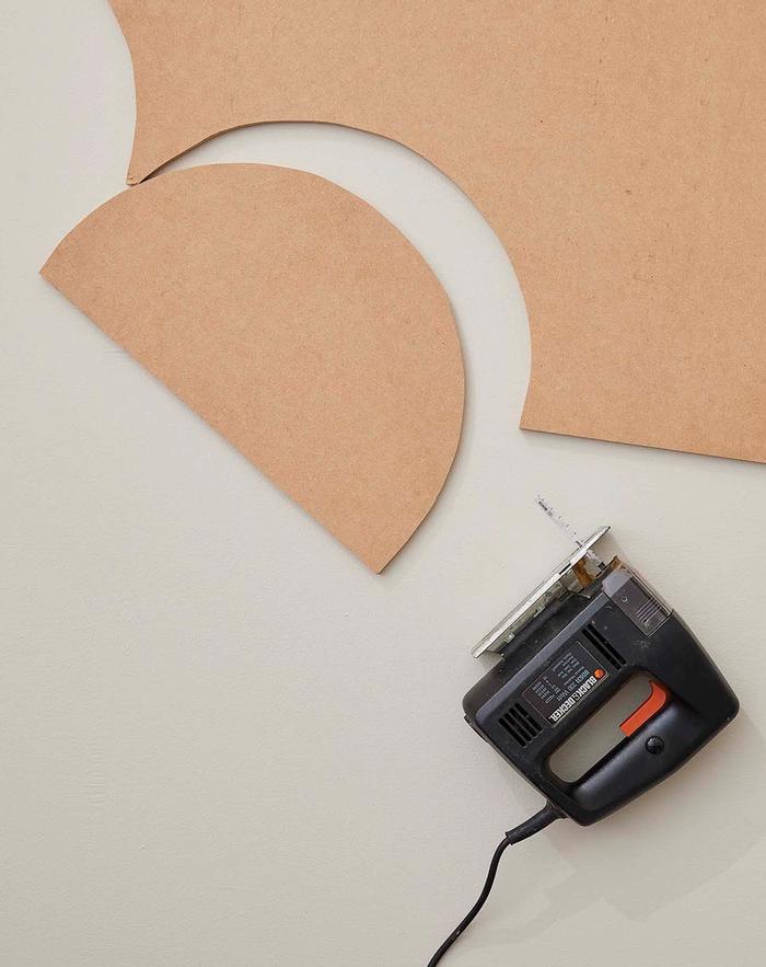 A piece of MDF board with an oval cut out and a jigsaw next to it