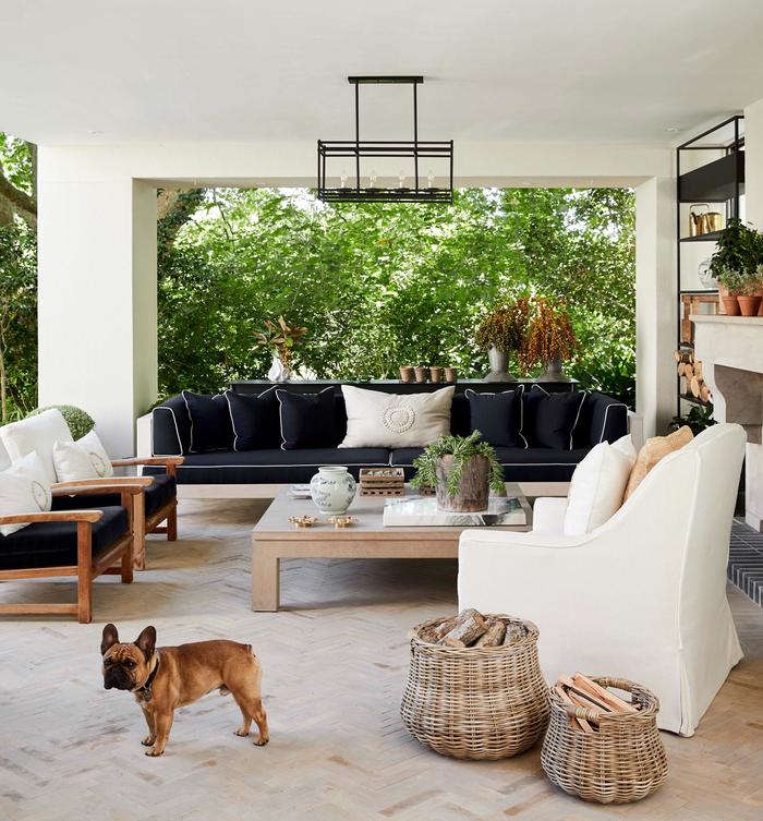 Outdoor room, with large pale rug, wicker baskets and a seating area around a coffee table