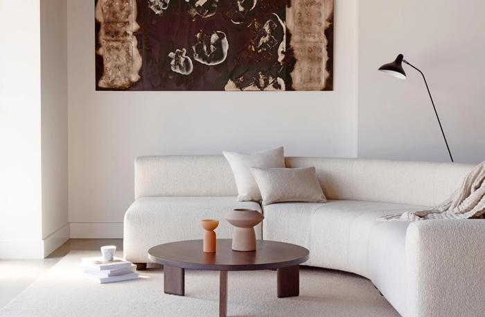 A lounge room containing a curved couch and a round coffee table.