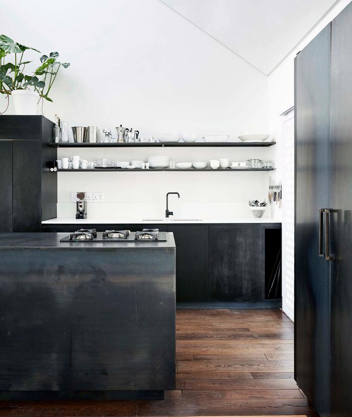 Black kitchen with white walls and wooden floorboards