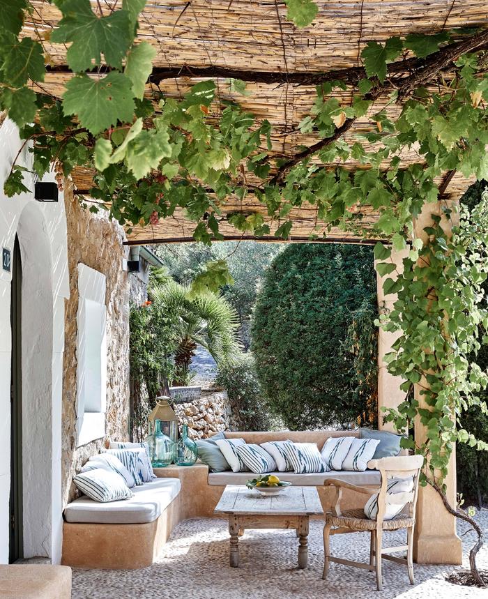 Outdoor space with inbuilt seating, the ceiling has plants hanging down from it, there are tiles on the ground