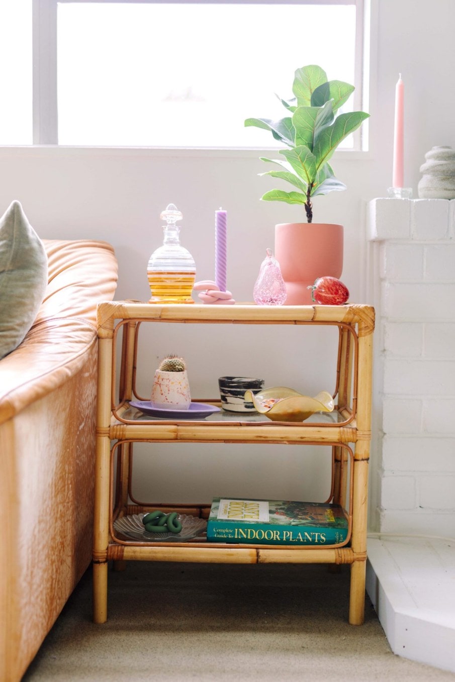 Wooden side table with pink and purple decorative pieces and a plant