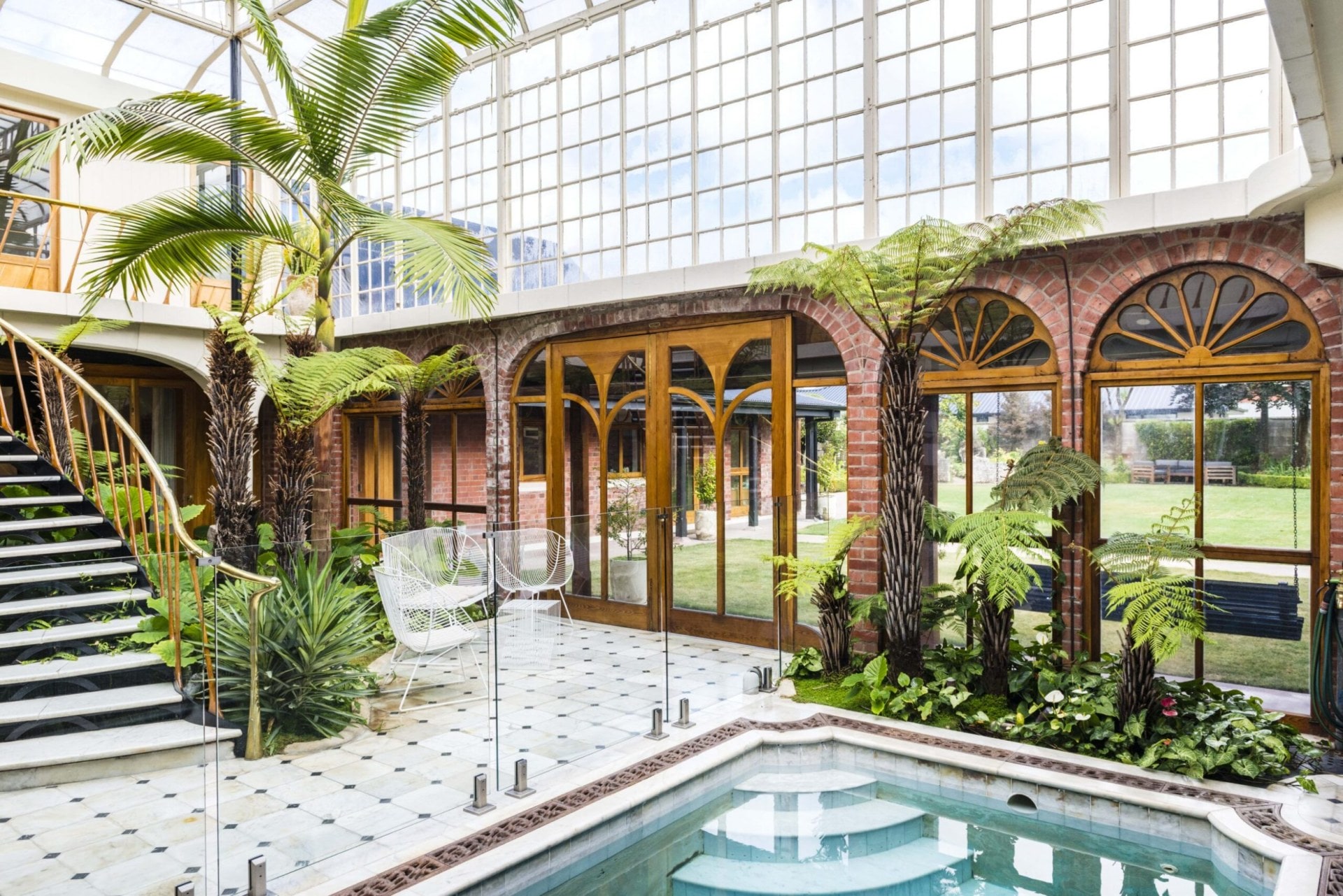 A large conservatory with arched windows and a blue pool