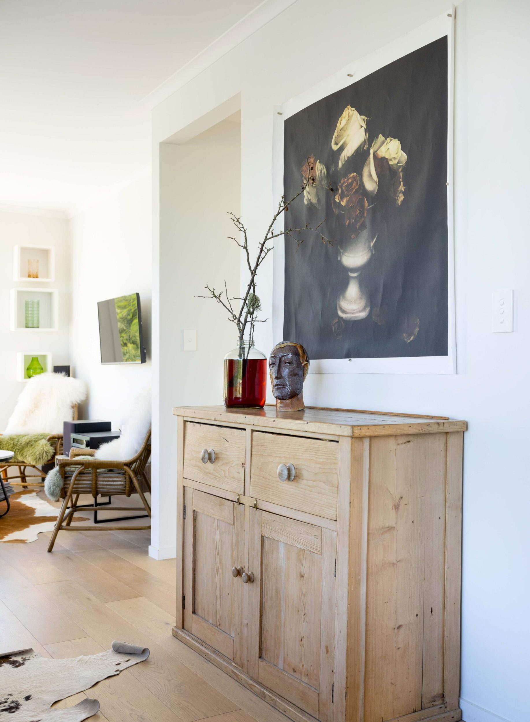 A wooden cabinet in a house with a large hanging artwork