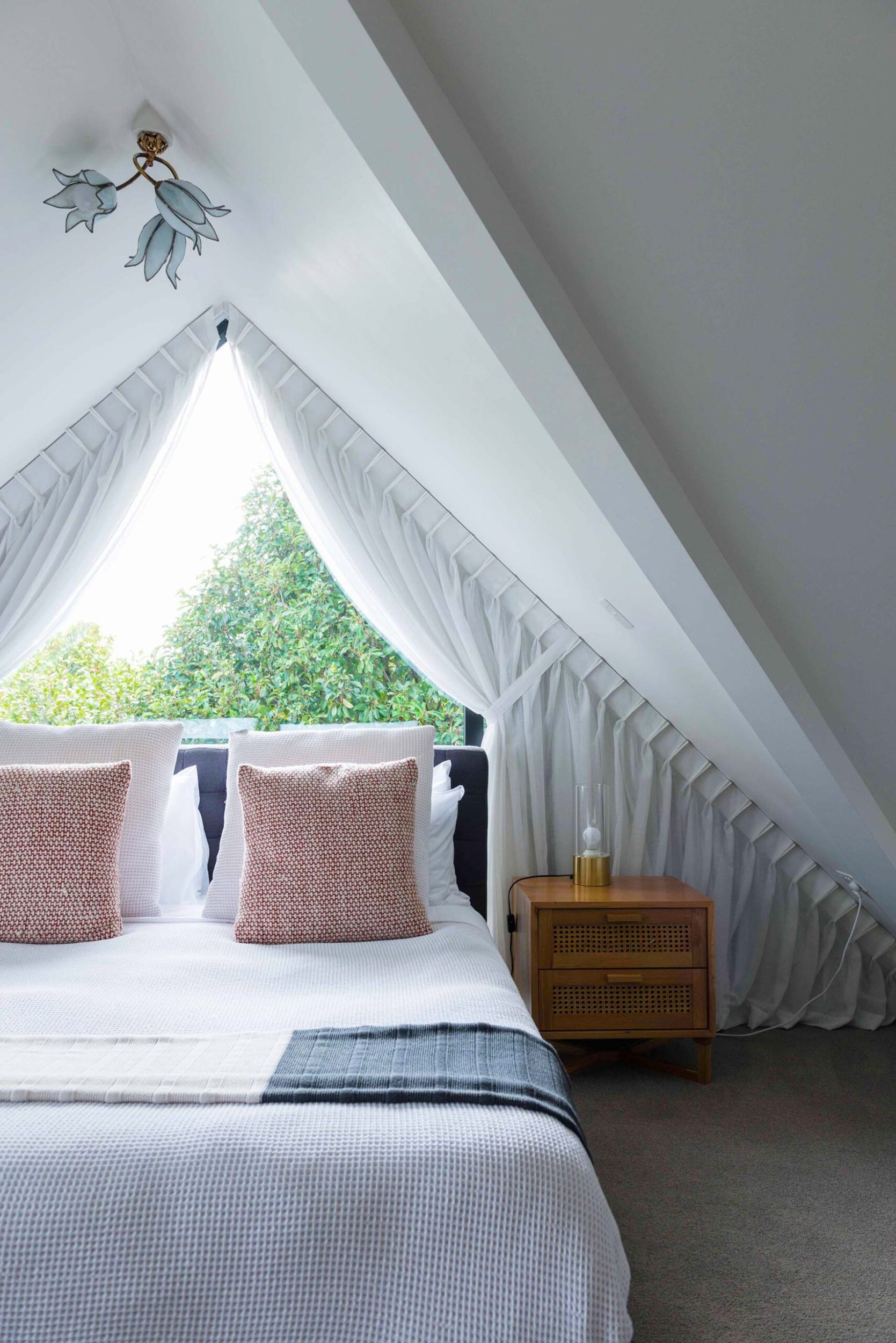 A bedroom with a white bed and an angled ceiling