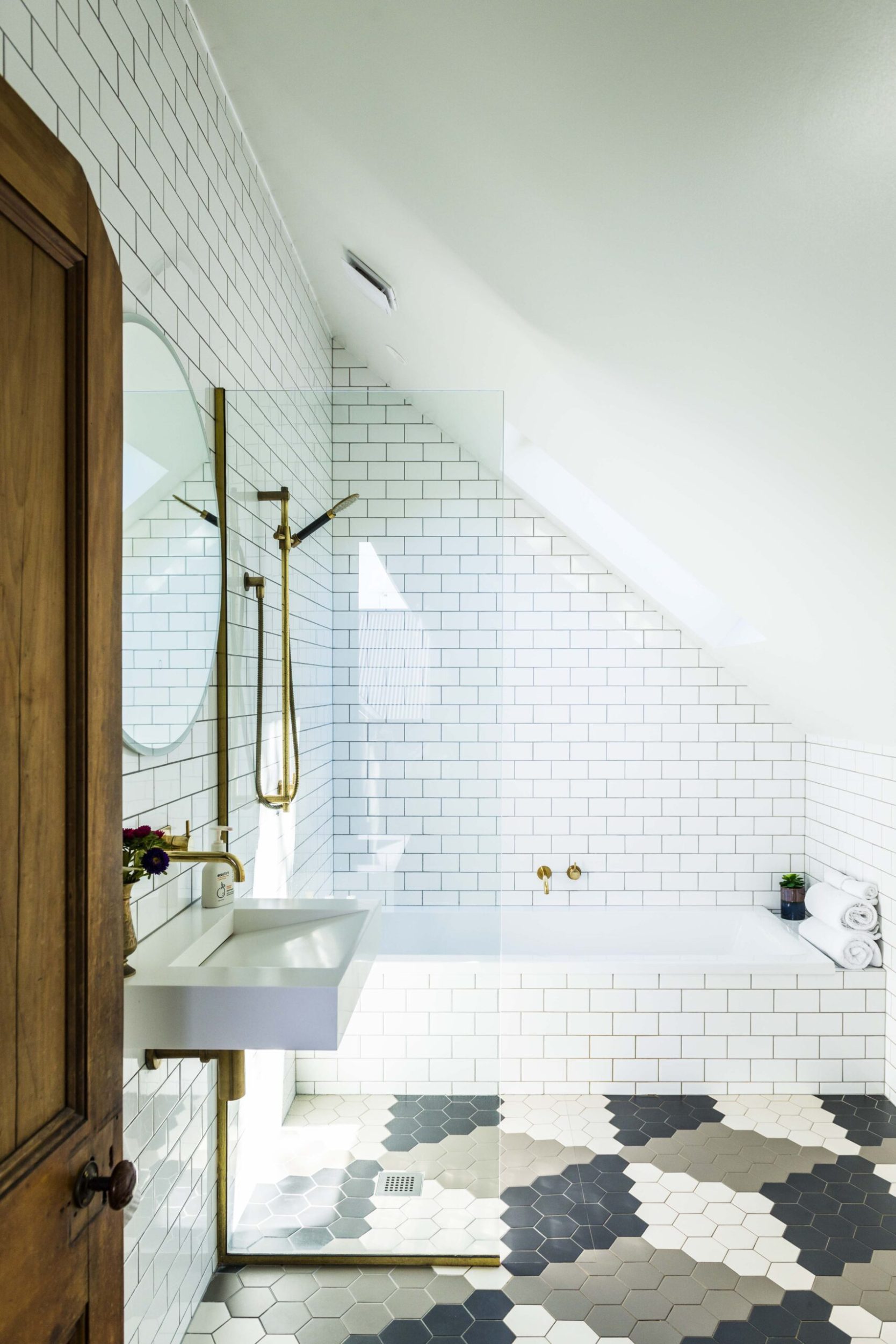 A white tiled bathroom with black and grey patterned tiled flooring