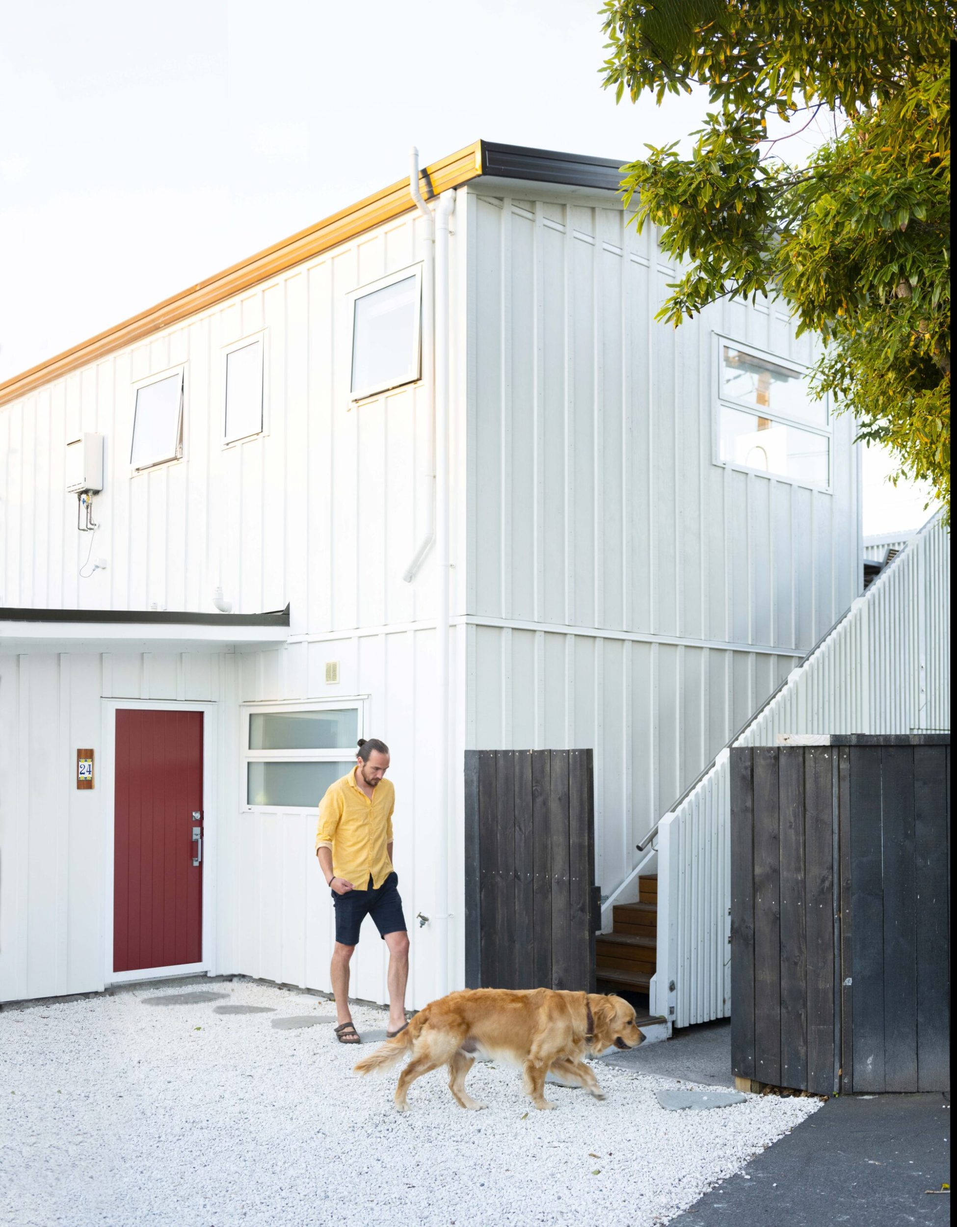 Man and dog walking in front of white house with red door