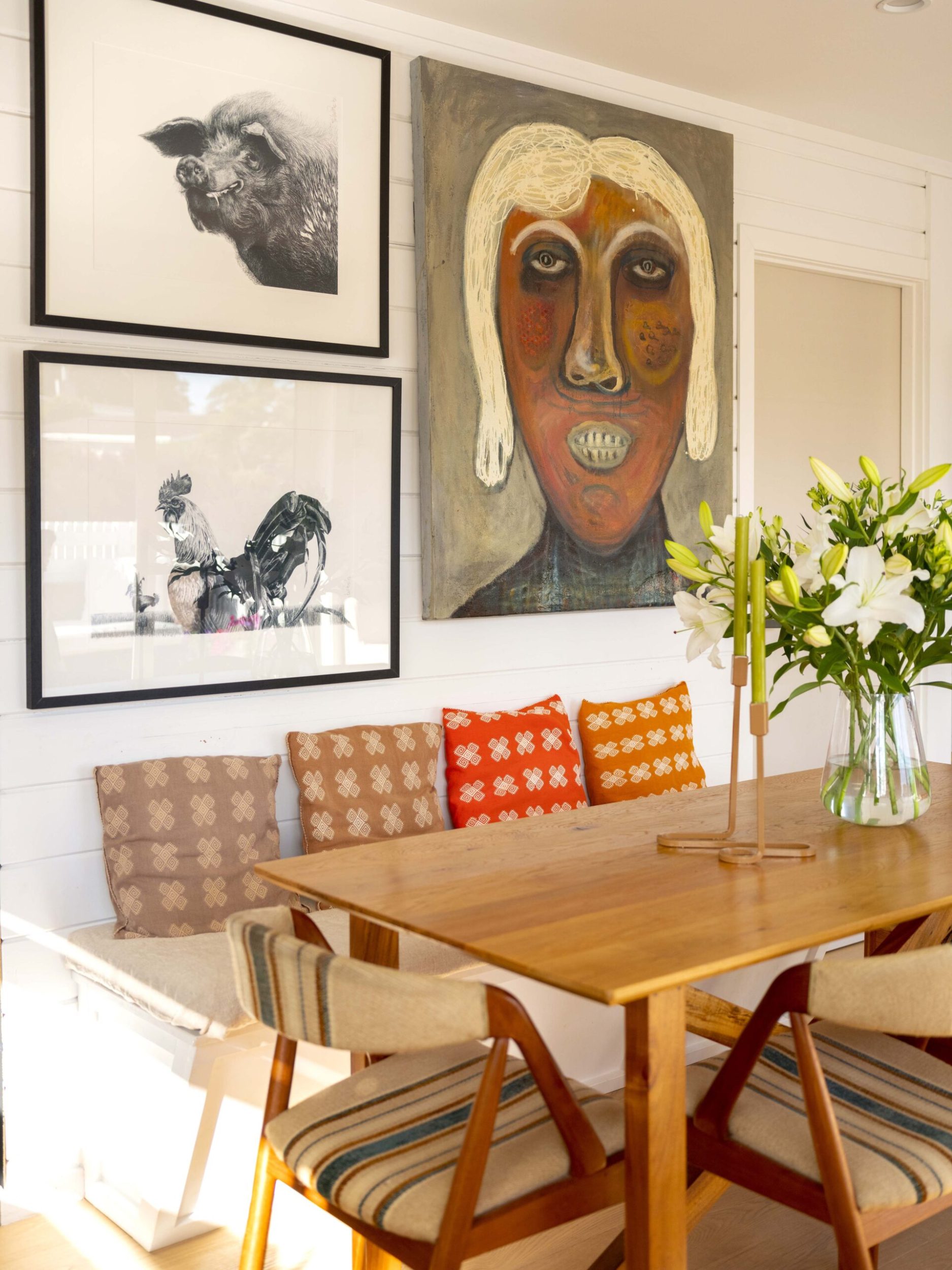 Gallery wall with painting and black and white photos above dining able