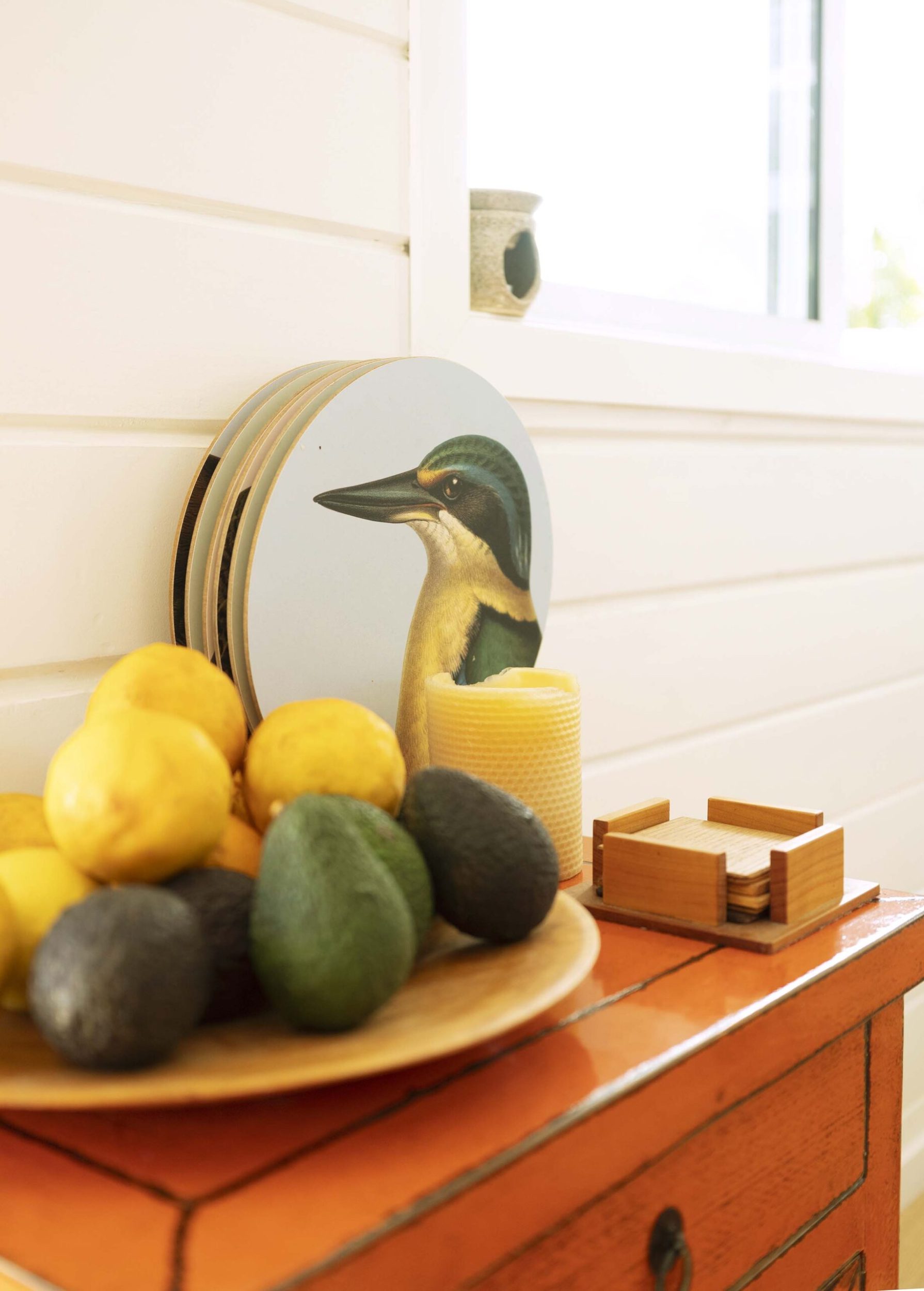 Plate of avocados and lemons with painted picture of bird behind