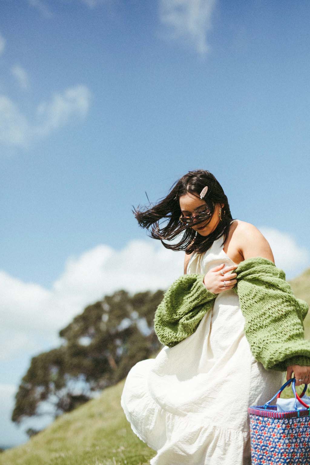 Woman wearing a white flowing dress and green cardigan