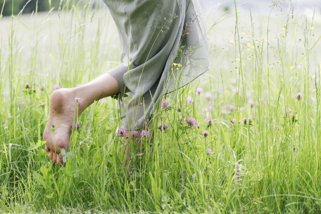 woman with bare feet walking through a green field