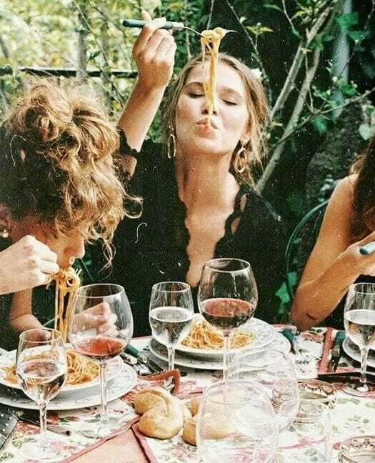 Woman enjoying an outdoor lunch with her friends consuming spaghetti with a beautiful set of cutlery. 