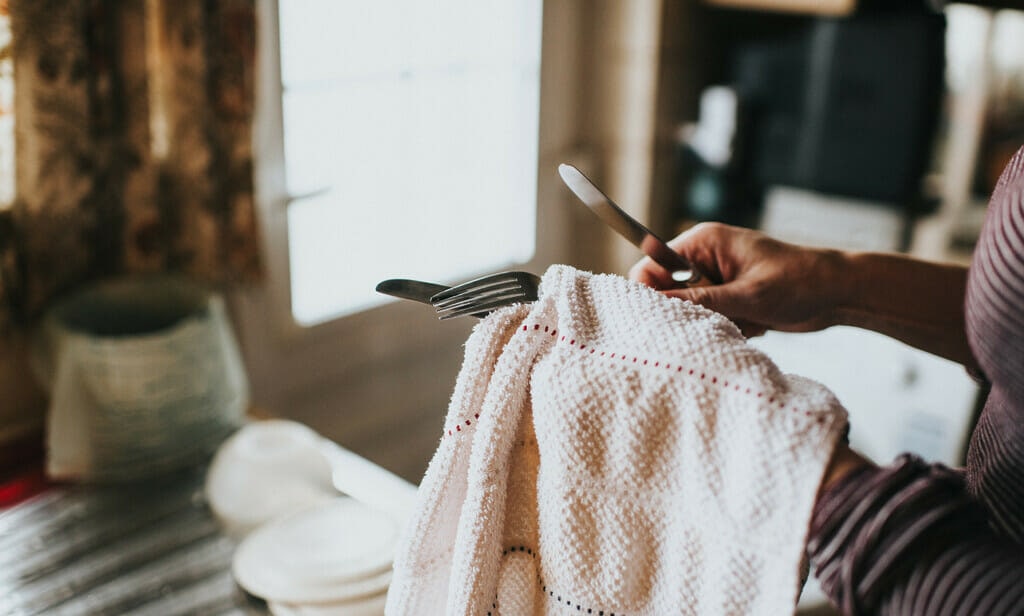 Woman cleaning a cutlery set of knives and forks. 