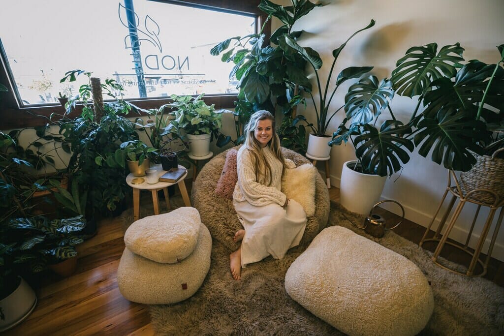 Women sitting on beanbag surrrounded by monsterra plants. 