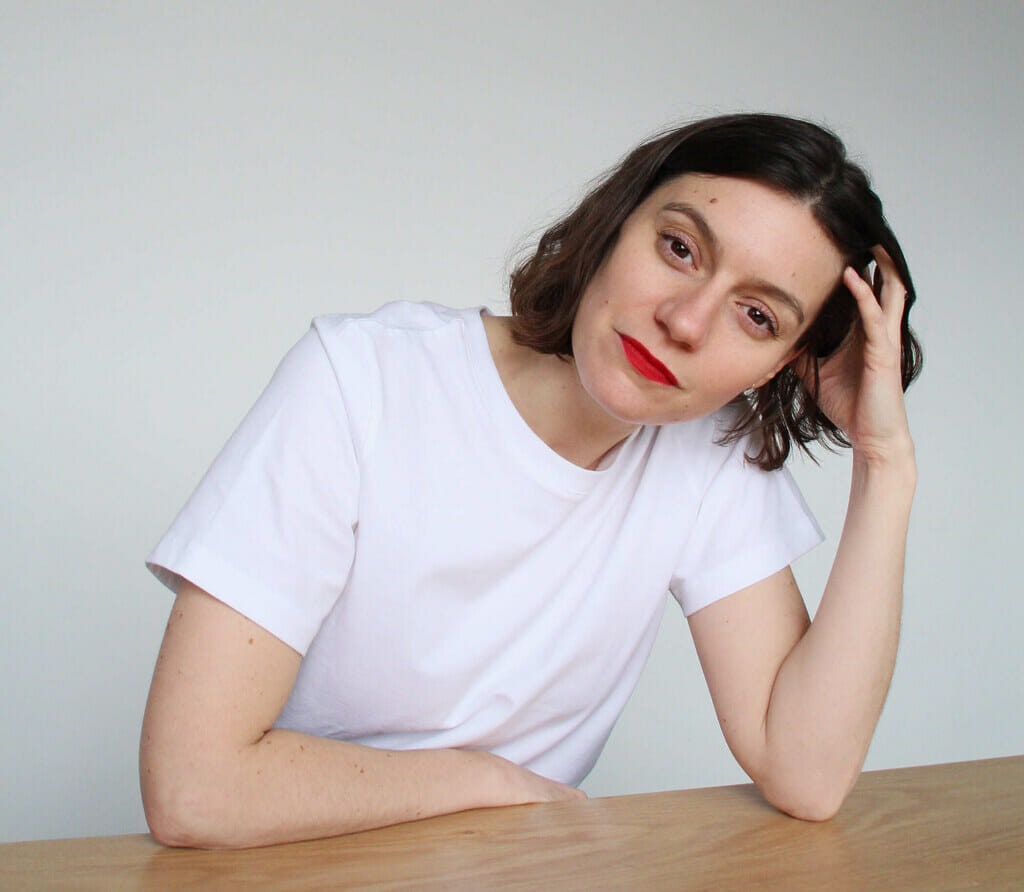 Marilou Dadat with her head in her hand sitting at wooden table.