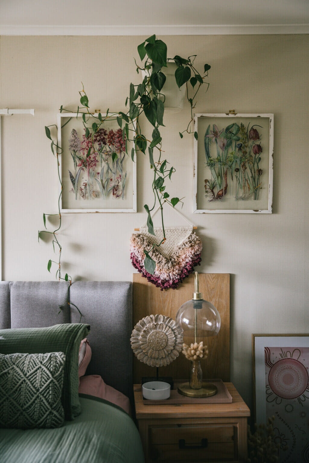 Bed with a green duvet and grey headboard. Interior designing is floral with shades of grey, green and pink. 