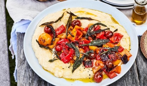 White plate with polenta and baked tomatoes