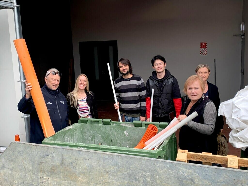 6 people standing around a green recycling bin. healthy home standards in NZ
