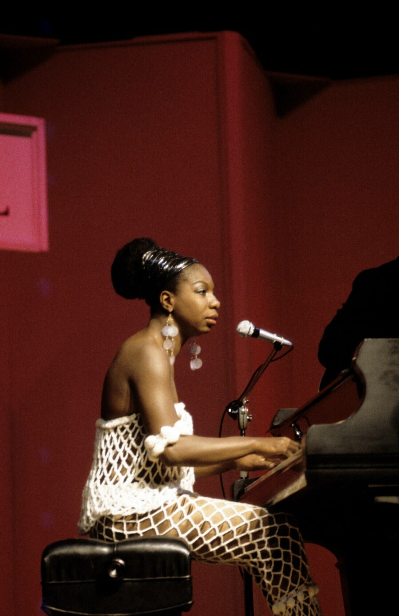 Nina Simone sitting at piano with microphone