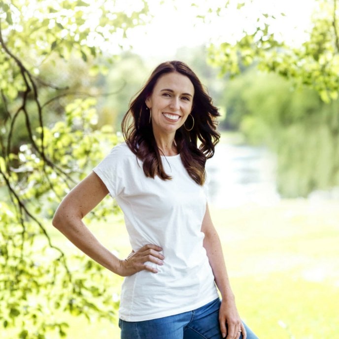 Jacinda Arden in jeans and white shirt with hand on her hip