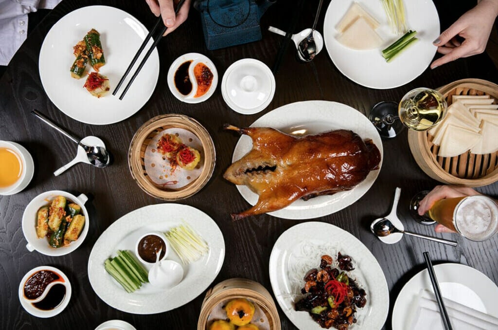 Chinese new year lunch at Huami. Black table with dumplings, cooked duck, assorted vegetables. 