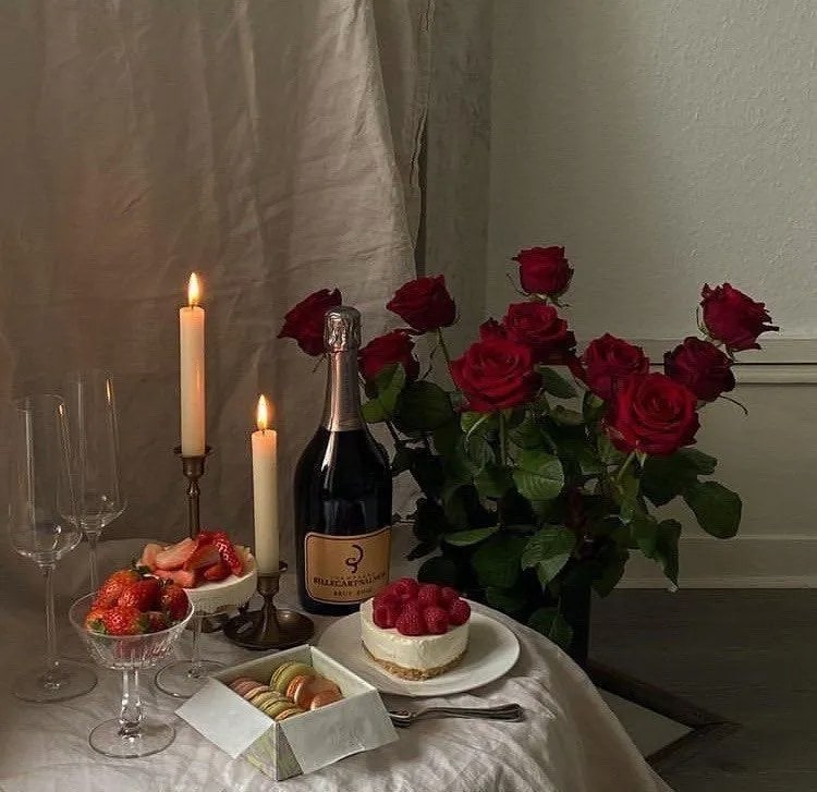 Romantic dinner with champagne, candles, strawberries, cake and red roses.