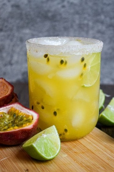 Passion Fruit Margarita with passionfruit and lime next to glass