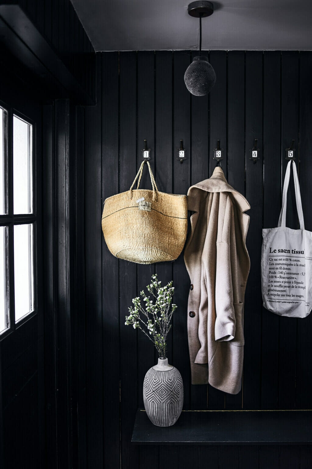 Coat room in a home with bags and a trench coat. 