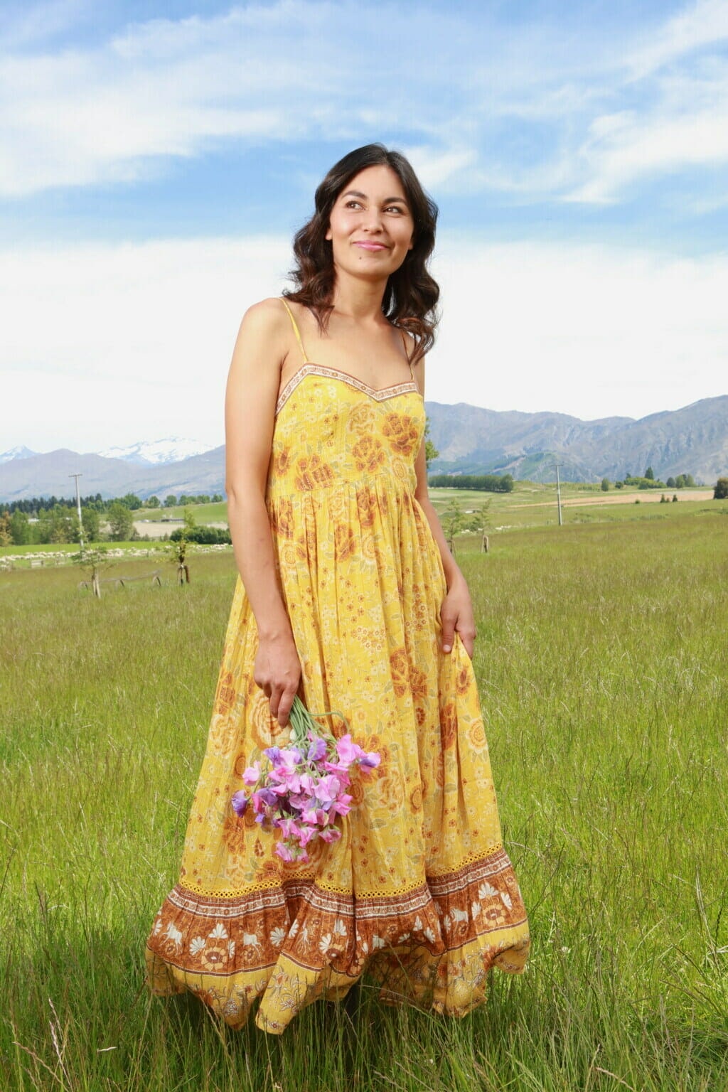 Nadia Lim in yellow dress holding pink flowers