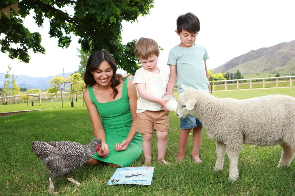 Nadia Lim in green dress and 2 young boys feeding a lamb
