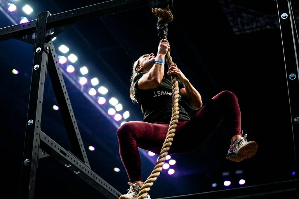 Women climbing up rope at crossfit games