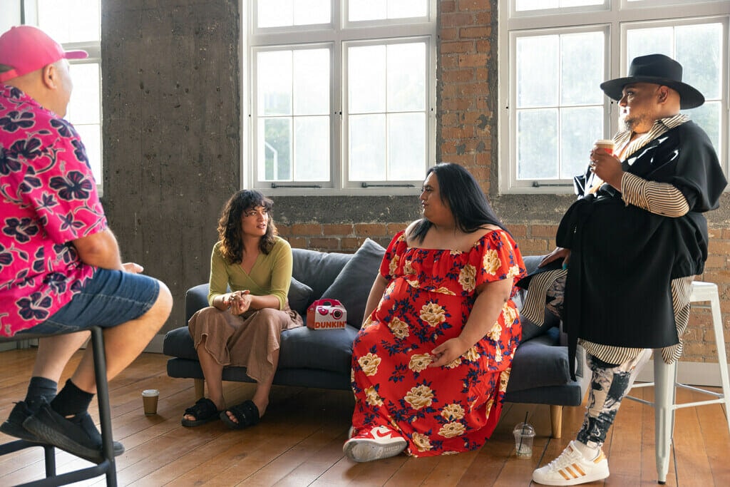 Brady Peeti, Awa Puna and Gee Pikinga standing together on a couch speaking to Aroha