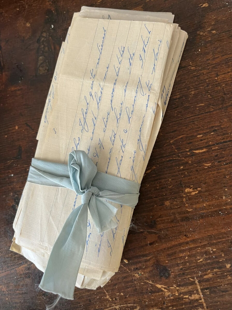 pile of letters on a wooden table with blue ribbon