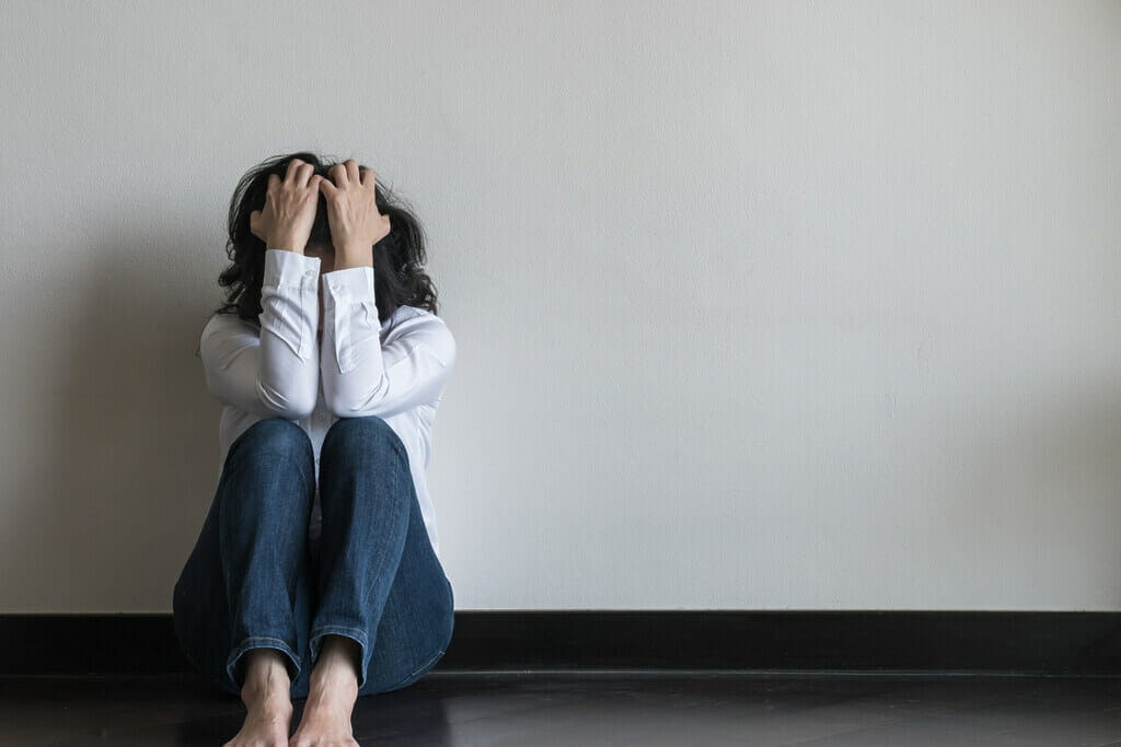 Women sitting on the floor with her head in her hands. 